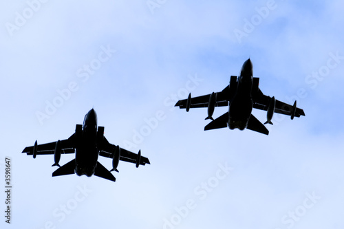 A silhouette of two Royal Air force RAF Panavia Tornado jet fighters against a blue sky.