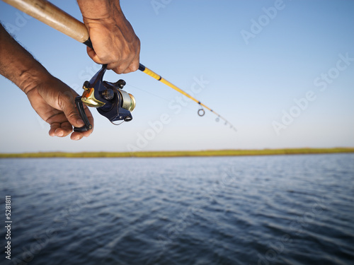 Hands holding fishing pole.
