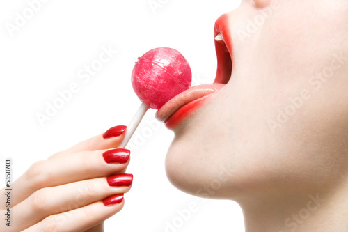 Woman licking sweet sugar candy closeup. Isolated on white.