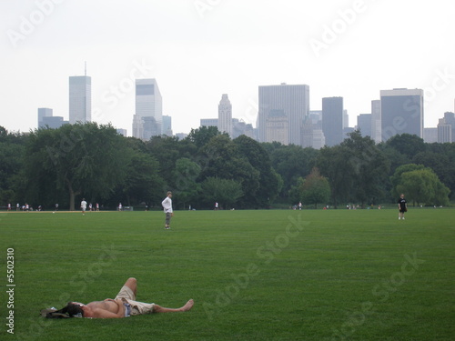 mann liegt auf wiese in central park in new york