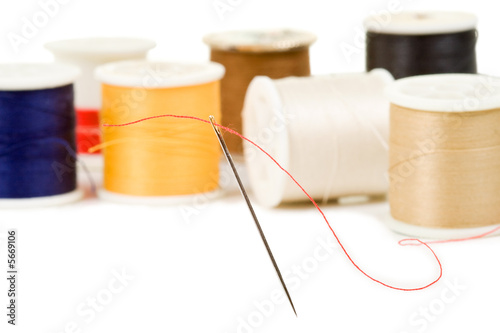 Sewing needle with various colored spools in background
