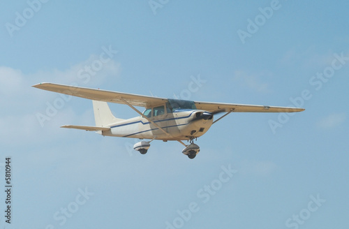 Light, white airplane mid-air on a blue sky background