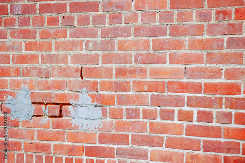 Red Brick Wall with Cracked Blocks and Concrete Patches