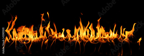 Tongues of fire in a panoramic view over a black background.