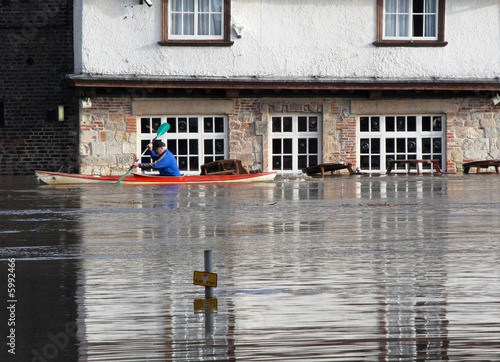 Canoeist paddles past flooded pub. River Ouse, York, UK.