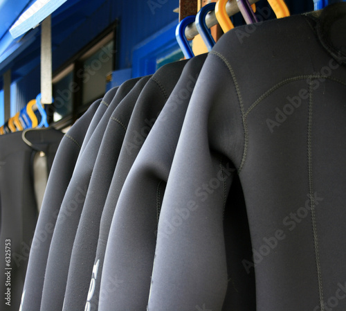A row of wetsuits hanging up to dry