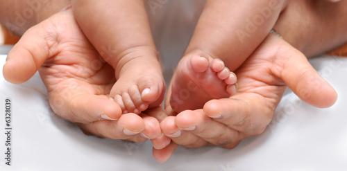 close up of a father's hand cradling babies feet