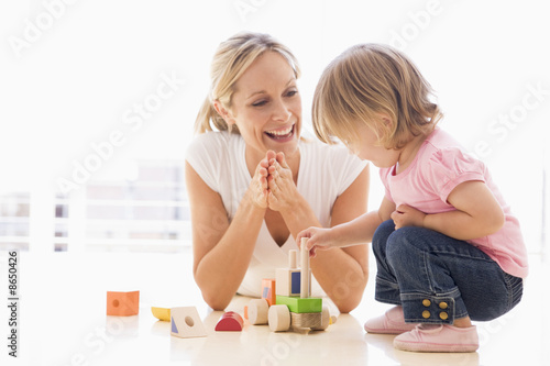 Mother and daughter indoors playing and smiling