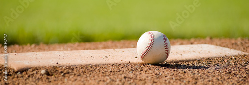 A white leather baseball lying on top of the pitcher's mound