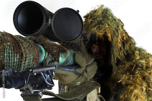 Sniper wearing a ghillie suit and shooting with sniper rifle.