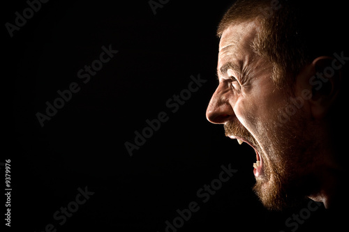 Face of angry man screaming isolated on black