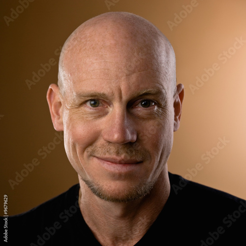 Close up studio shot of bald man with goatee and mustache