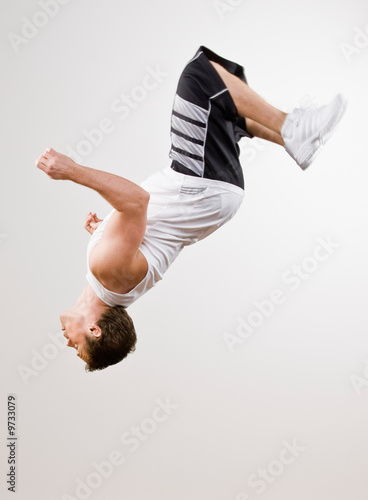 Skilled athlete in sportswear doing somersault in mid-air