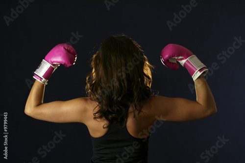 Young woman flexing with pink boxing gloves.