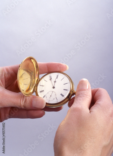 A woman's hands setting time on a gold pocket watch