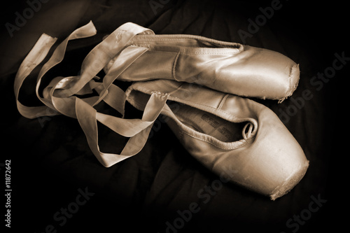 Worn ballet pointe shoes on a dark background.