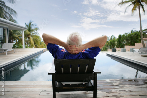 Homme âgé assis sur une chaise au bord d'une piscine