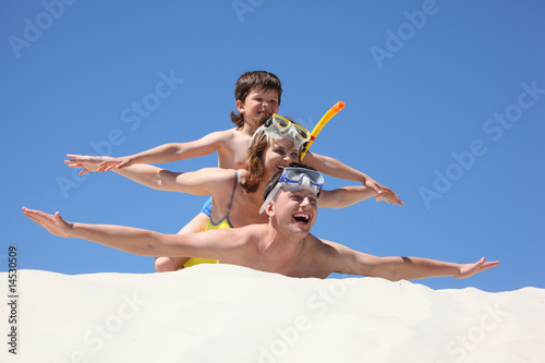 family with son lying on sand with hands up