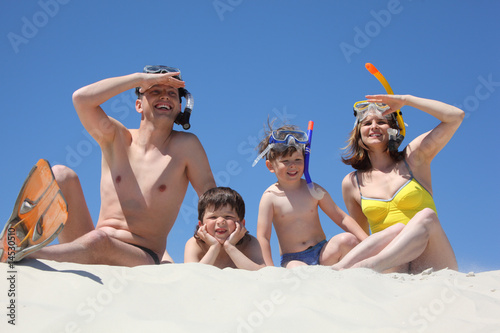 family with snorkeling masks sitting on sand