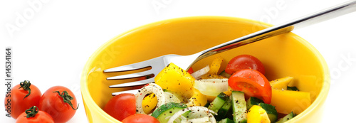 vegetable salad in a yellow bowl with fork and tomato