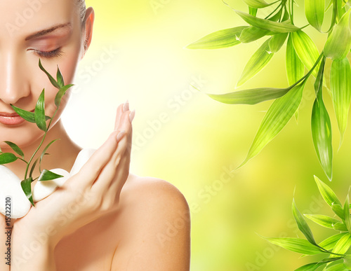 Beautiful young woman holding plant growing up through stones..