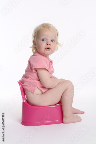 Toddler girl is sitting on a pink potty