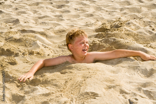 Kinder spielen an Strand im Sand und graben sich ein