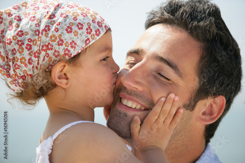 Portrait d'une petite fille embrassant un homme sur la joue