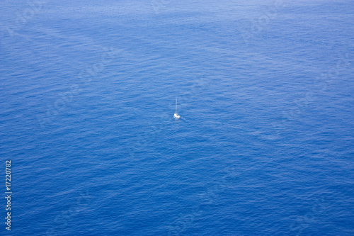 Single boat sailing in a vast ocean