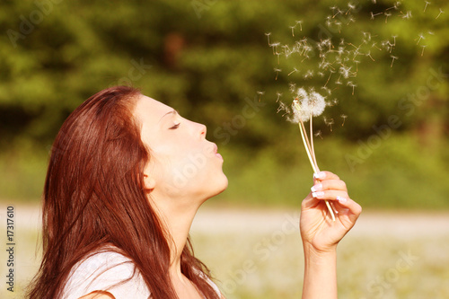 young woman ist blowing a dandelion