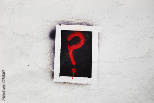 red question sign painted inside black square on cracked wall