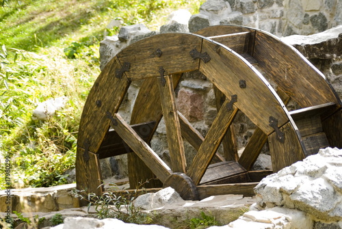 Old watermill with a wooden wheel and stone walls