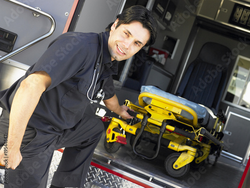 Paramedic removing empty gurney from ambulance