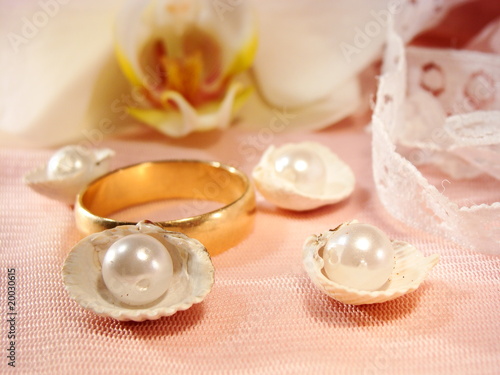 gold wedding ring on pink satin with orchid and pearls
