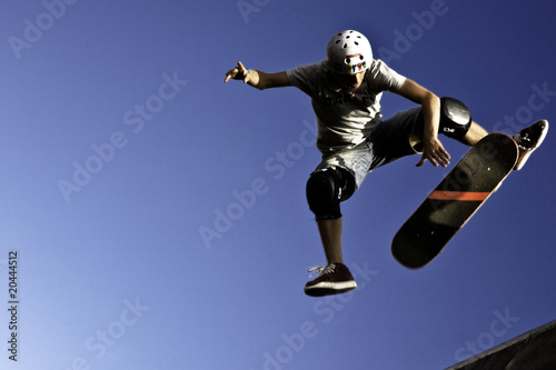 Un patinador está en el aire, realizando un truco en una rampa. Concepto de emoción y adrenalina, ya que el skater es capturado en una pose dinámica, mostrando su habilidad y atletismo.