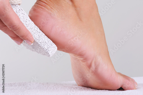woman scrubbing foot by pumice