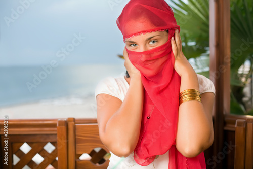 young woman in yashmak sitting in an arbour on seacoast