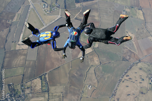 Three skydivers in freefall high up in the air