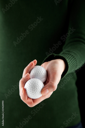 closeup shot of a female hand holding two golf balls