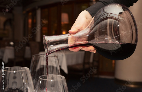 Waiter pouring red wine from decanter