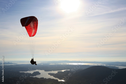 Paraglider flying over Norwegian landscape