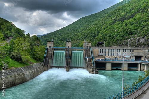 hydroelectric power-plant dam on a river with water overflowing the dam after heavy rain