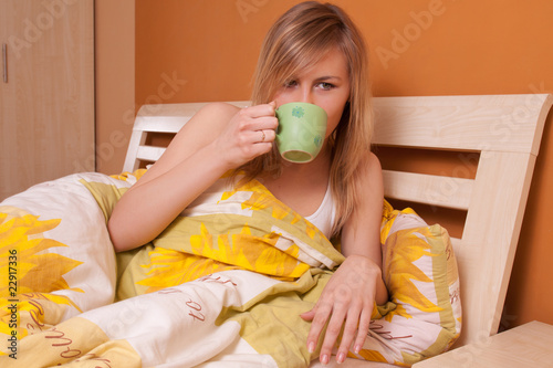 Bautiful woman drinking coffee or tea at bedroom on bed