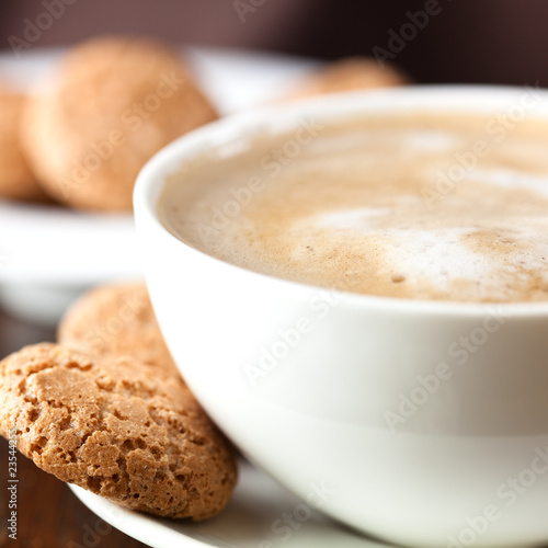 Cup of delicious coffee with milk froth and biscotti