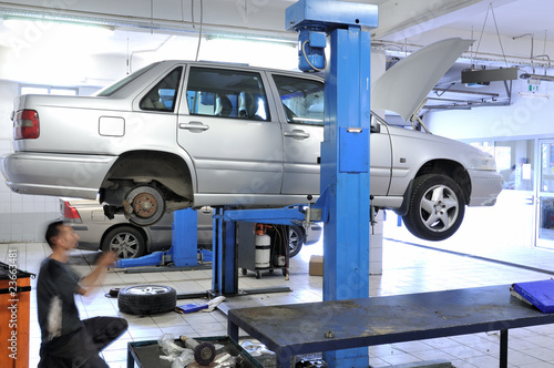 Auto mechanic changing tire under the car.