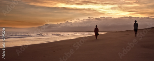 Two blurred silhouettes walking on a beautiful beach at sunset