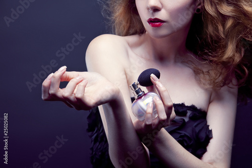 beautiful woman applying perfume on her body