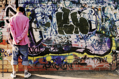 Teenager against graffiti wall.