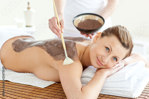 Delighted caucasian woman receiving a beauty treatment with mud