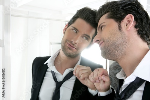 Handsome narcissistic young man looking in a mirror